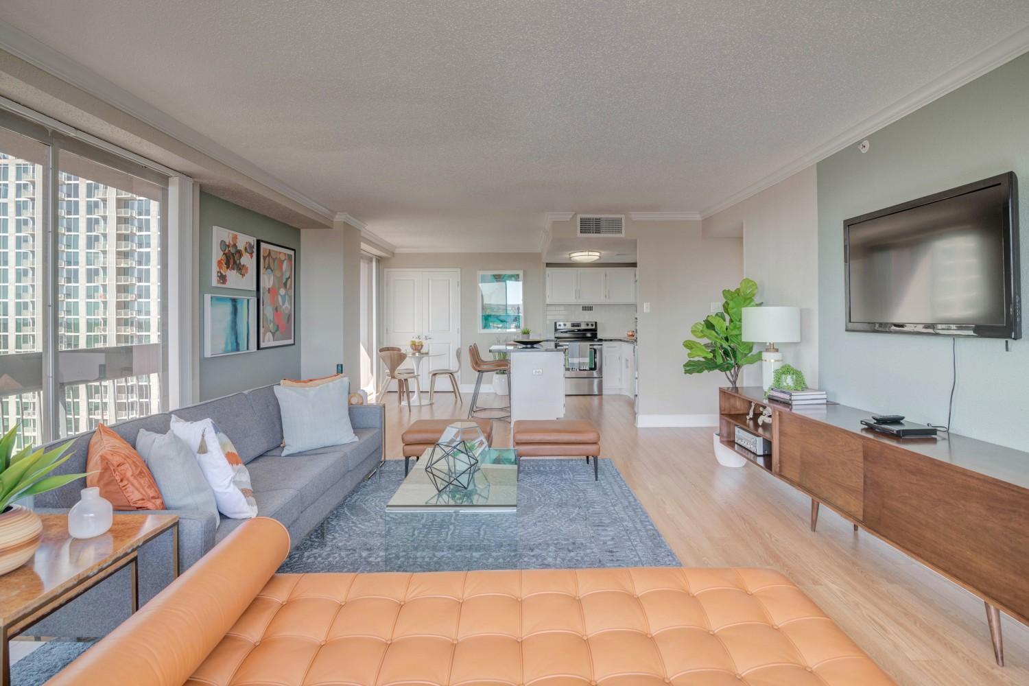 Open living area with large windows and view into the kitchen and dining