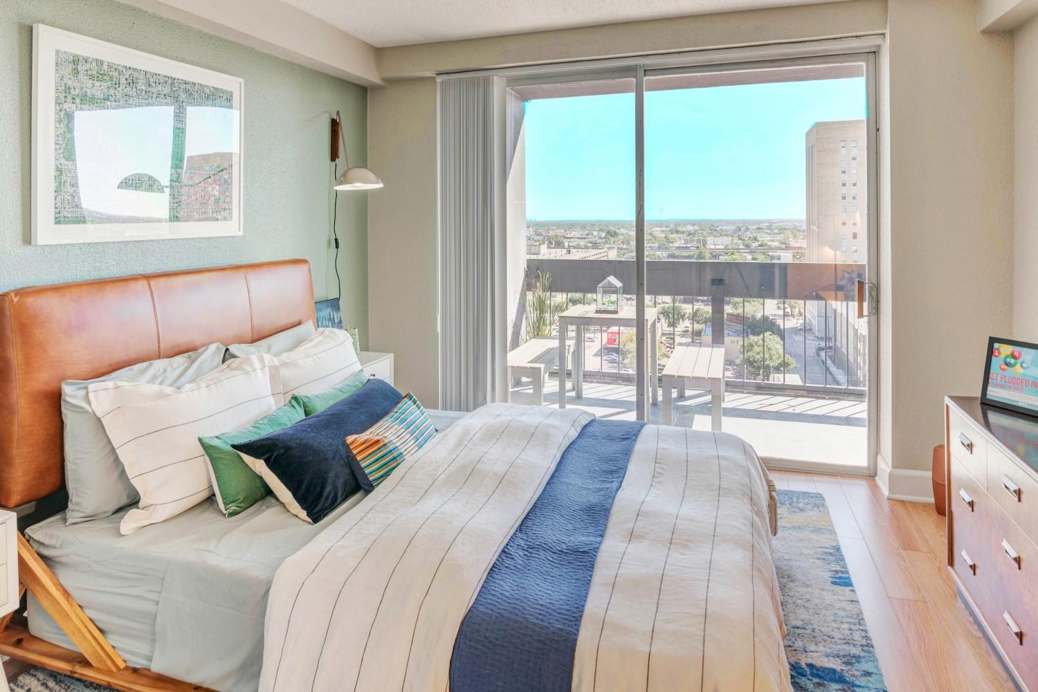 Bedroom with glass balcony doors and skyline view